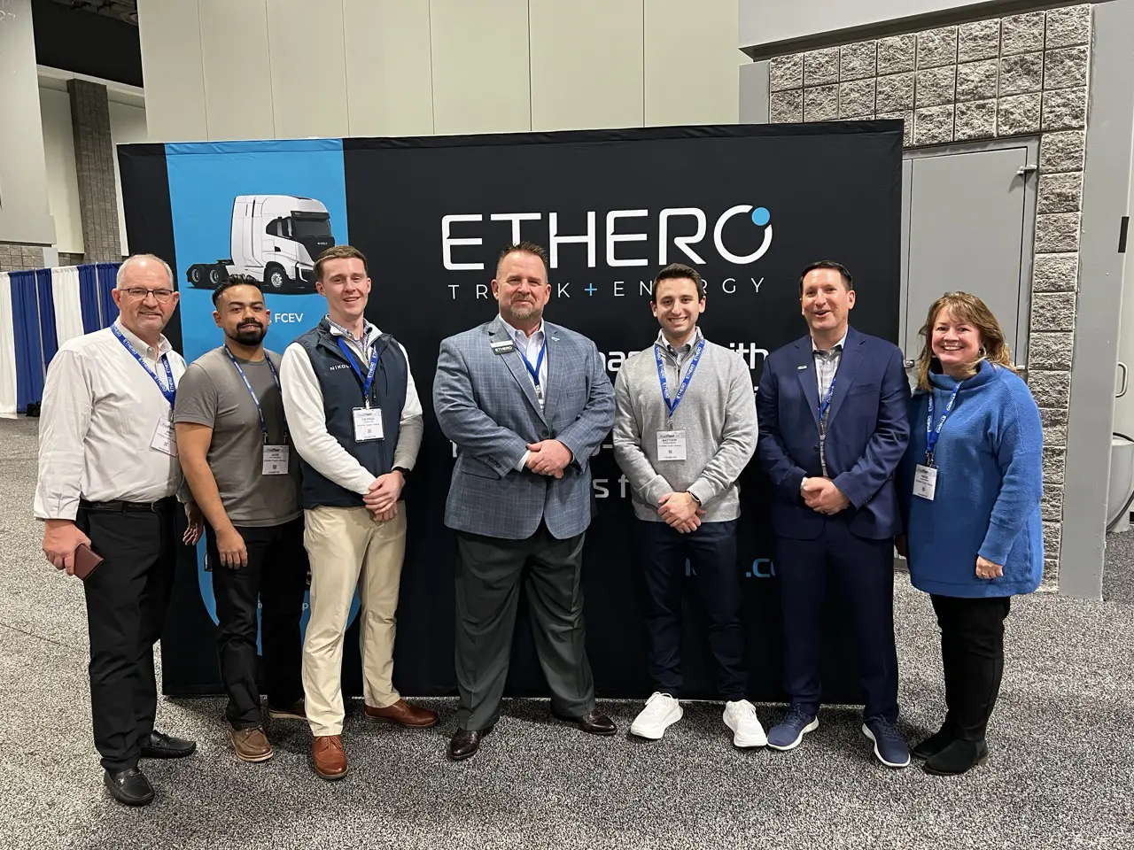 7 adults standing in front of a banner that says ETHERO