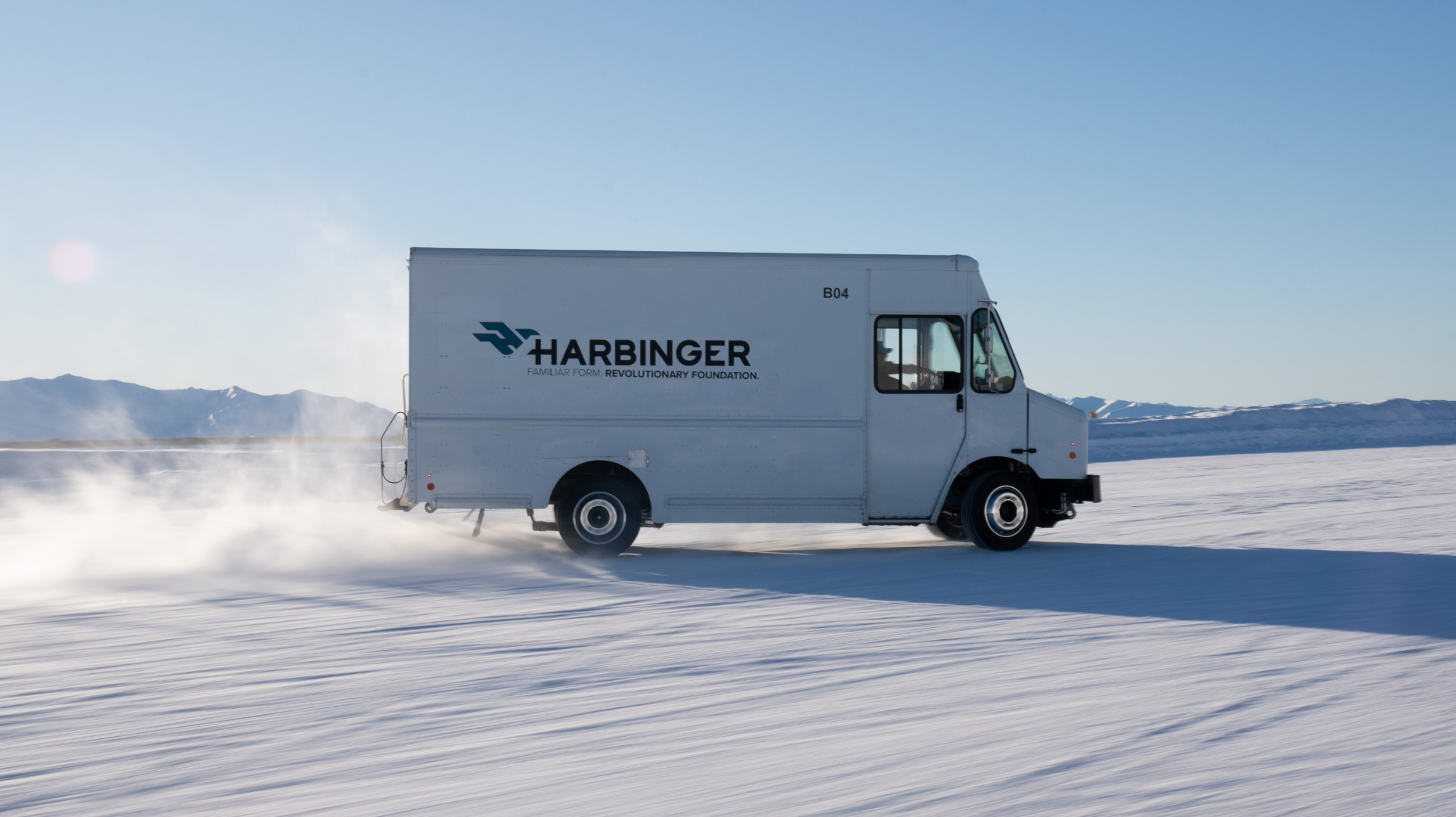 A Harbinger truck driving across a white, sandy surface.