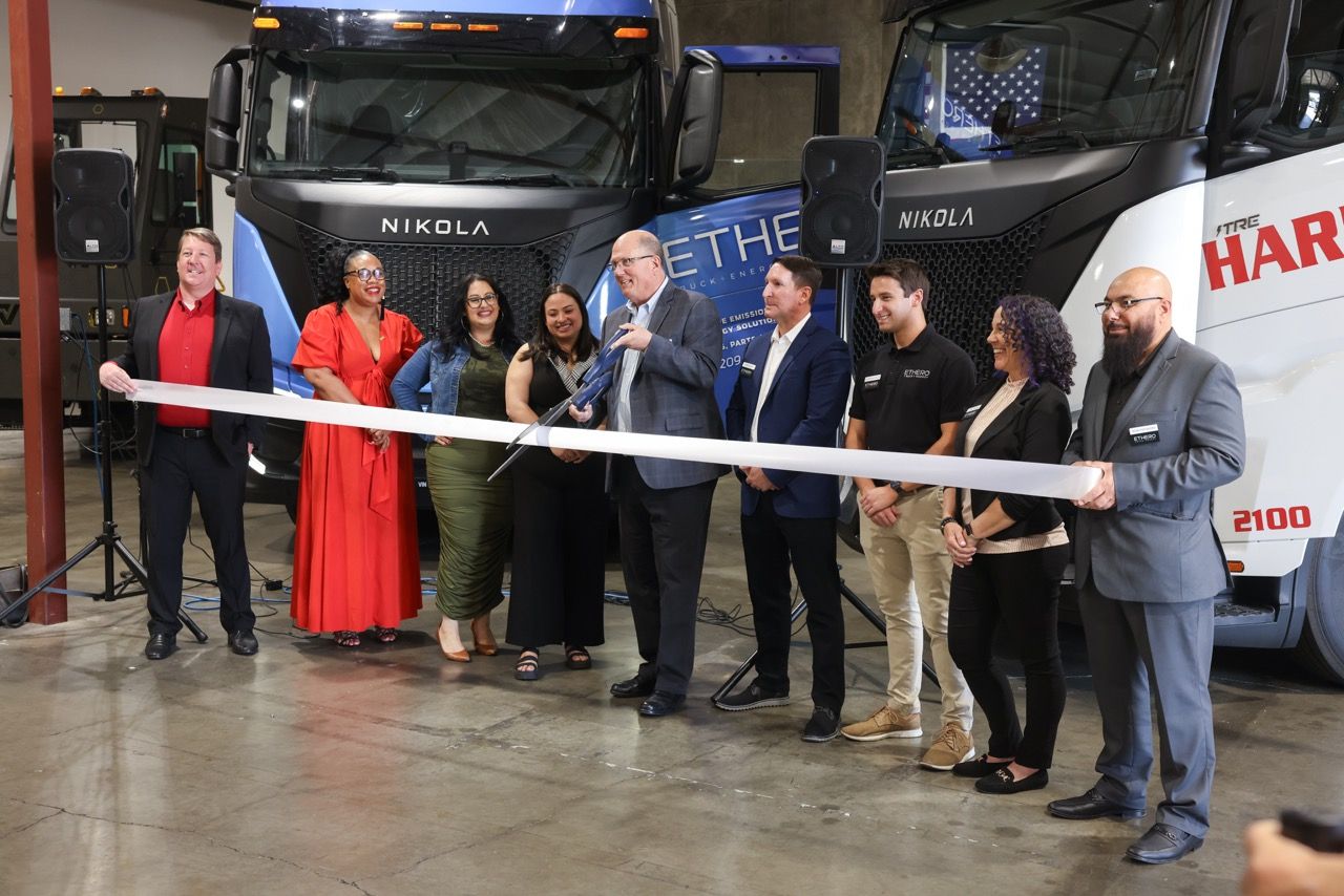 A group of people gathered for a ribbon cutting ceremony.